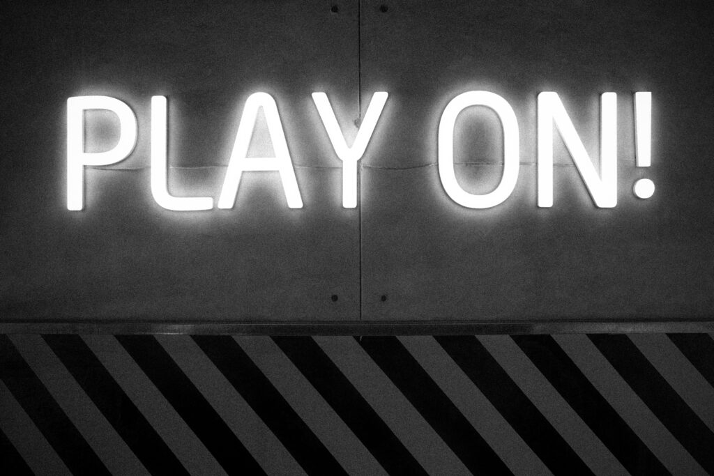 A striking black and white 'Play On' neon sign on a textured wall.
